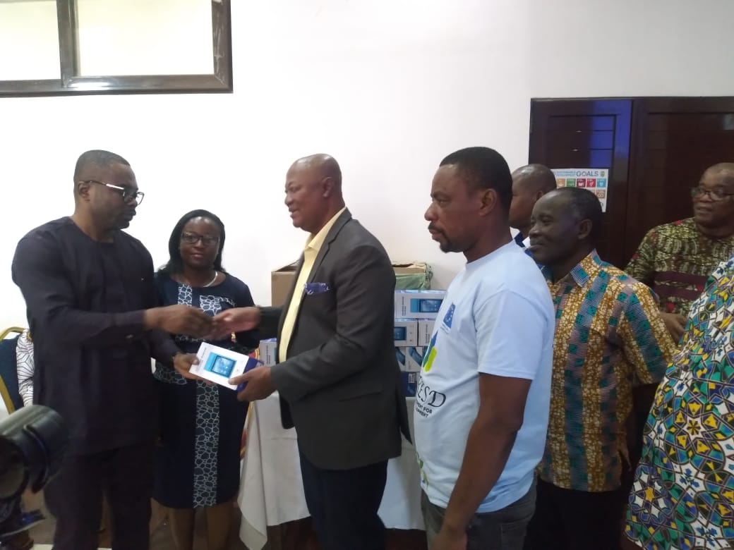 Kumasi Mayor, Sam Pyne (right) presenting the PoS device to one of the KMA revenue officers at the Assembly's conference room